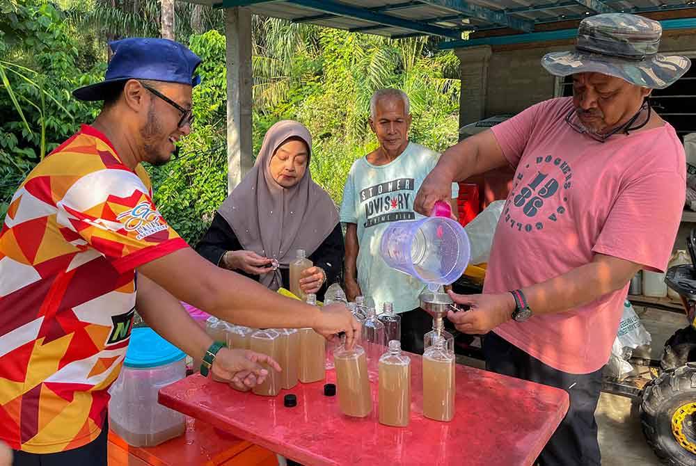 Ab Aziz (kanan) dibantu ahli keluarga mengisi air nira atau lebih dikenali air tuak pandan ke dalam botol untuk dijual. - Foto Bernama