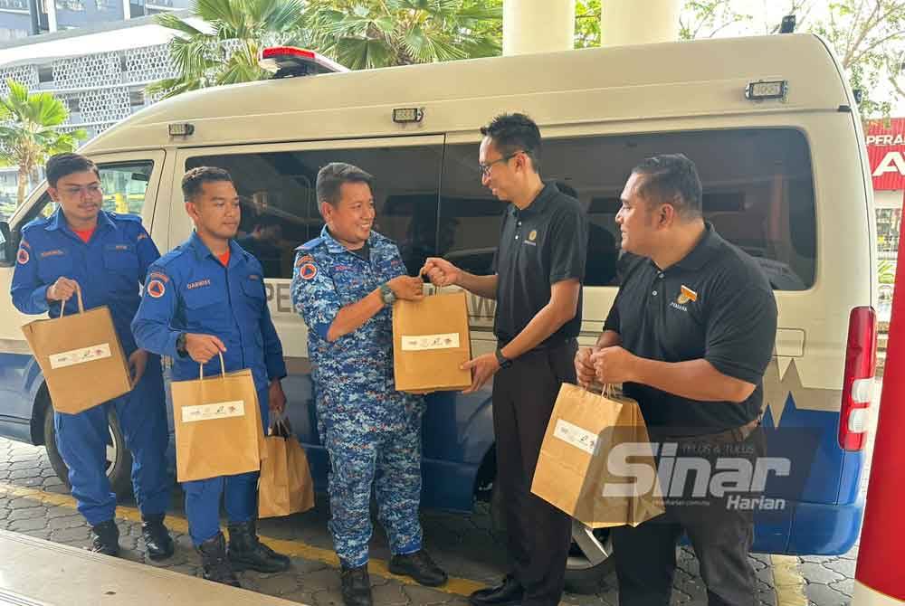 Mohd Iqmal (dua dari kanan) menyampaikan bubur lambuk kepada Rohaizad (tiga dari kiri) pada Khamis.