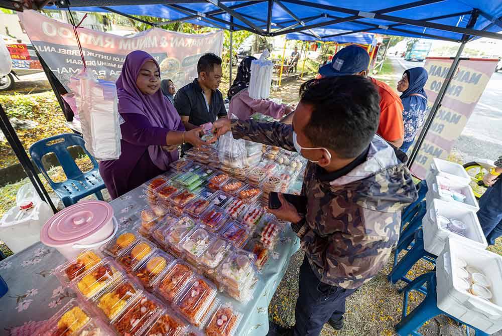 Nurul (kiri) menyantuni pelanggan di gerainya. Foto Bernama