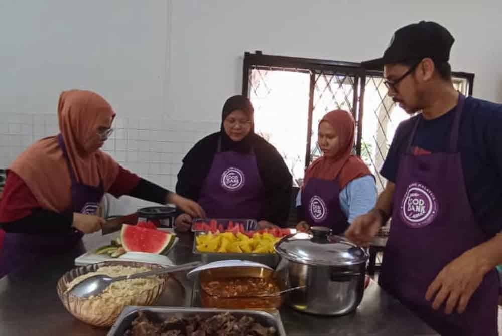 Mohd Azrul (kanan) bersama sukarelawan menyediakan nasi daging untuk pengunjung Kafe Makan Percuma di Jalan Sultanah, pada Jumaat.