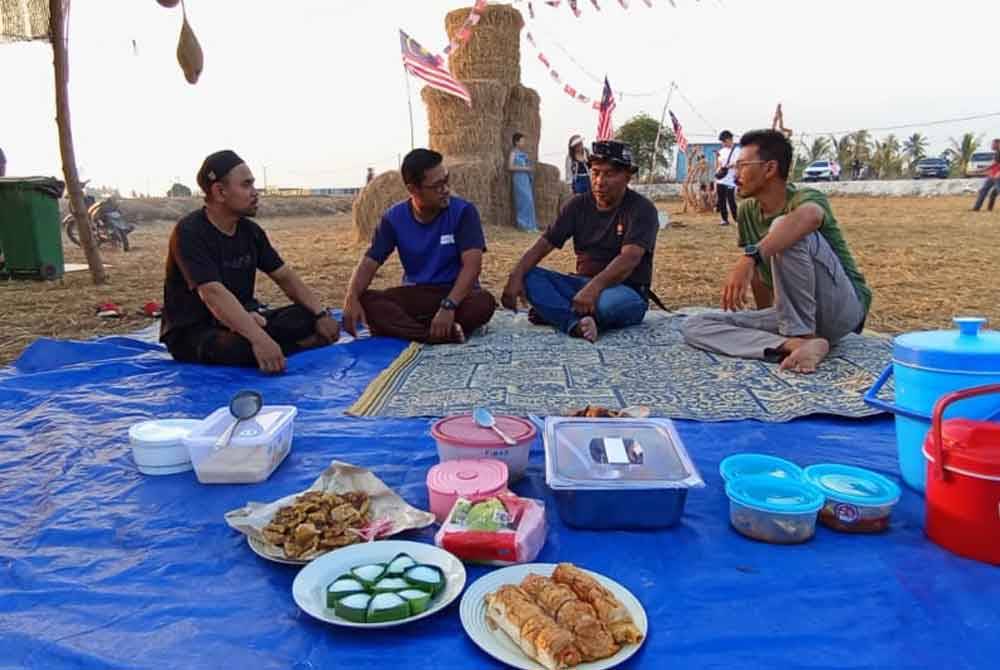 Sekumpulan anak muda mengambil inisiatif berbuka puasa di kawasan sawah padi dihiasi jerami gulung di Kampung Kelompang.