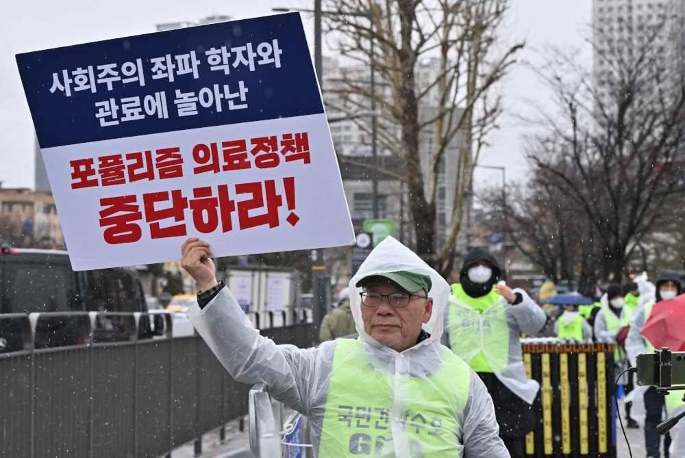 Seorang doktor memegang plakad tertera 'hentikan dasar perubatan populis' ketika protes di Seoul pada 21 Februari lalu. Foto AFP