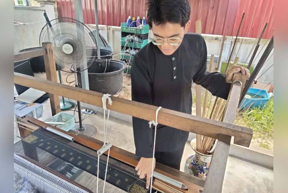Muhammad Zafran menunjukkan corak bunga yang ditenun.