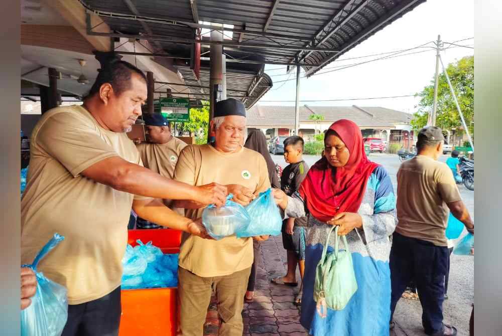 Hambali ( kiri) mengedarkan juadah berbuka kepada penduduk Taman Mergong Jaya 1 dan 3 di sini pada Sabtu.
