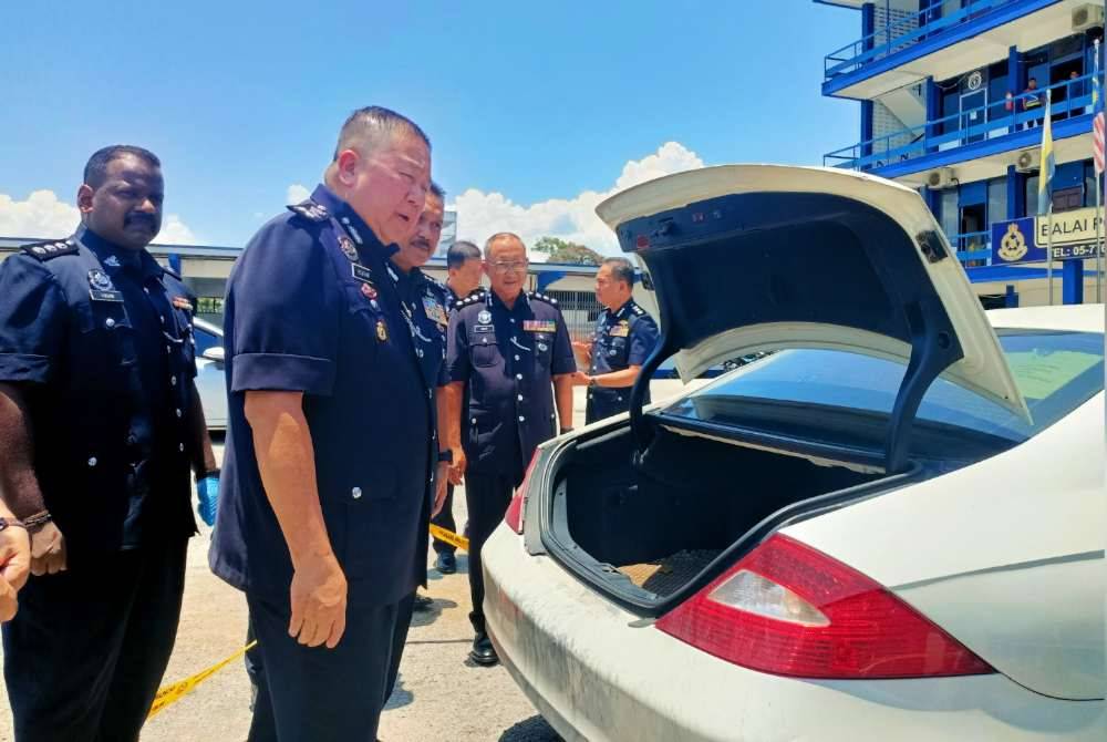 Kok Chin memeriksa kereta jenis Mercedes Benz yang dirampas dalam serbuan di kawasan parkir sebuah bangunan di Kuala Kangsar pada Sabtu.
