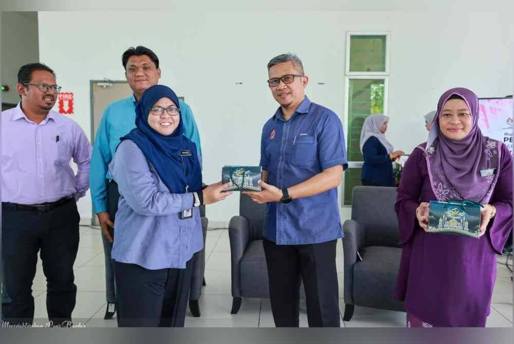 Ismasuhaimi (dua dari kanan) menyerahkan pek kurma kepada warga kerja KEDA sempena bulan Ramadan.