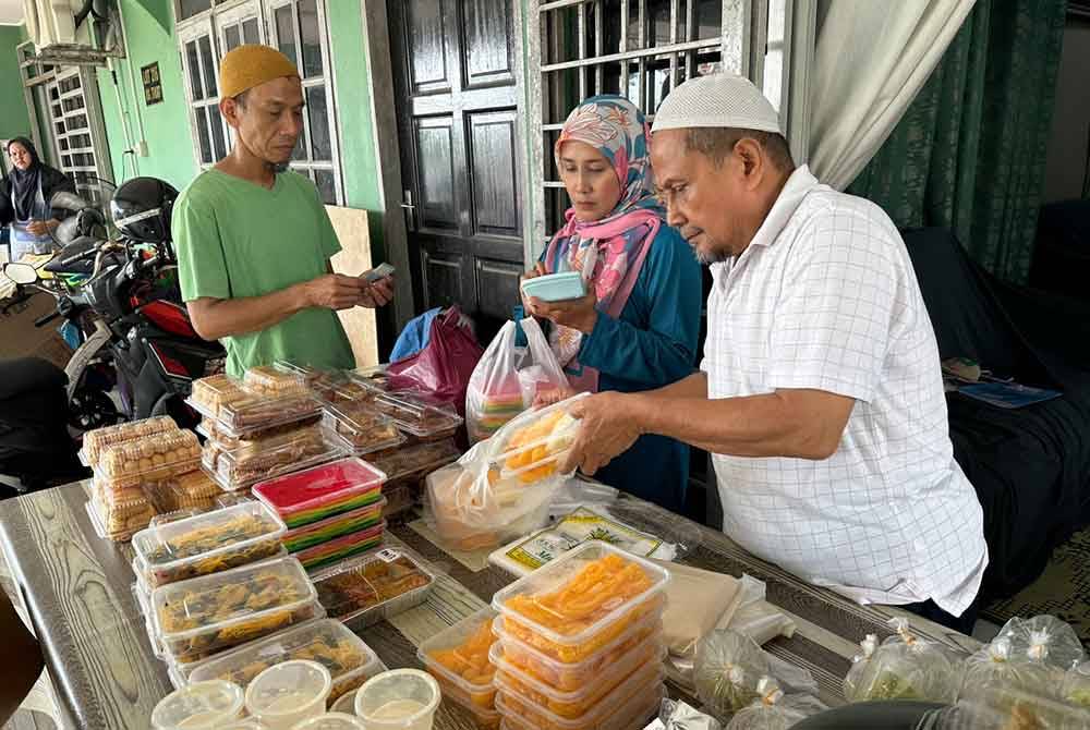 Mohammed (kanan) melayani pelanggan yang membeli kuih jala mas.