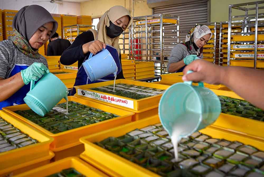 Para pekerja menuang santan adunan bagi melengkapkan kuih Tepung Pelita di Taman Tasik Tambahan, Ampang hari ini.