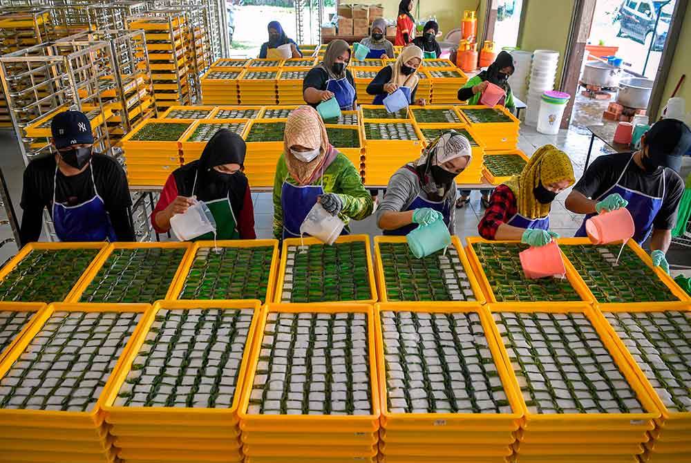 Para pekerja menuang santan adunan bagi melengkapkan kuih Tepung Pelita di Taman Tasik Tambahan, Ampang hari ini.