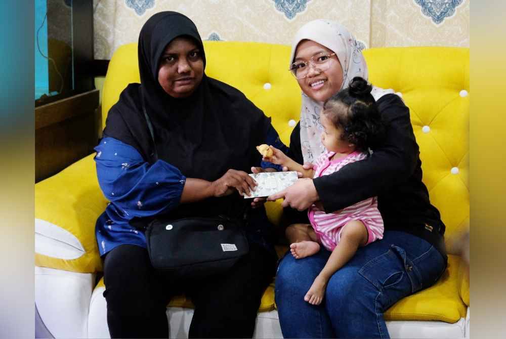 Nor Komariah (kiri) menyerahkan sumbangan kepada Noreen ketika ditemui di Taman Desa Baru, di sini, pada Isnin.