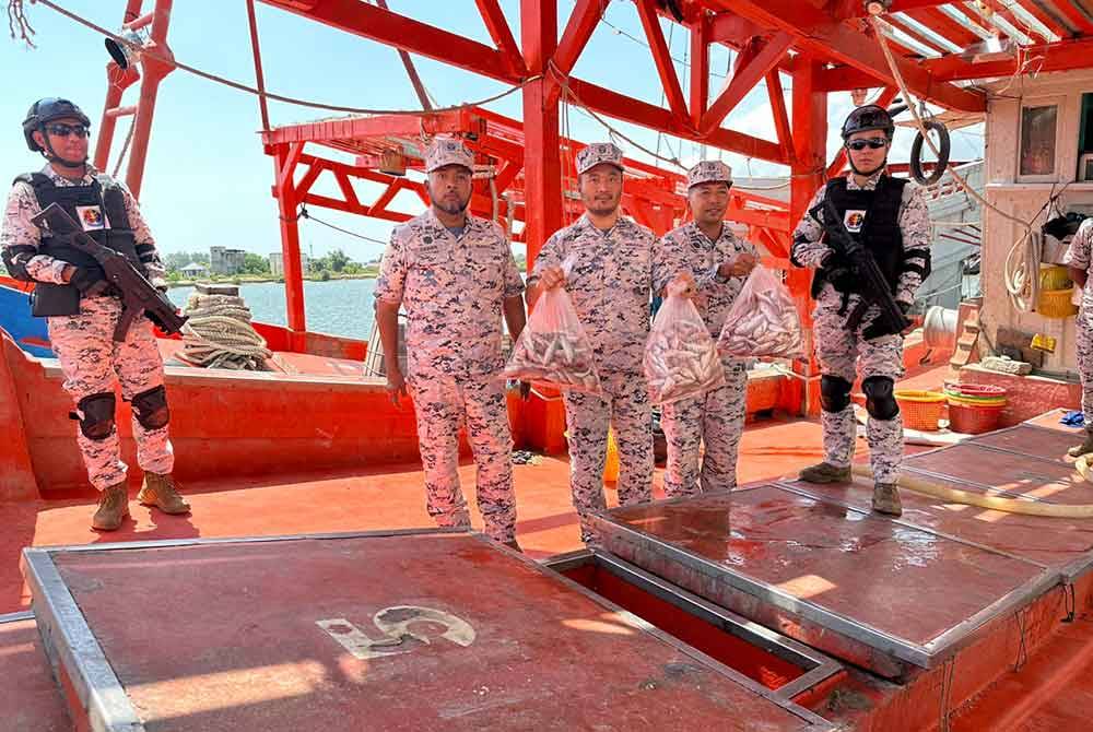 Erwan Shah (dua dari kiri) dan anggota menunjukkan hasil tangkapan ikan yang dirampas pihaknya.