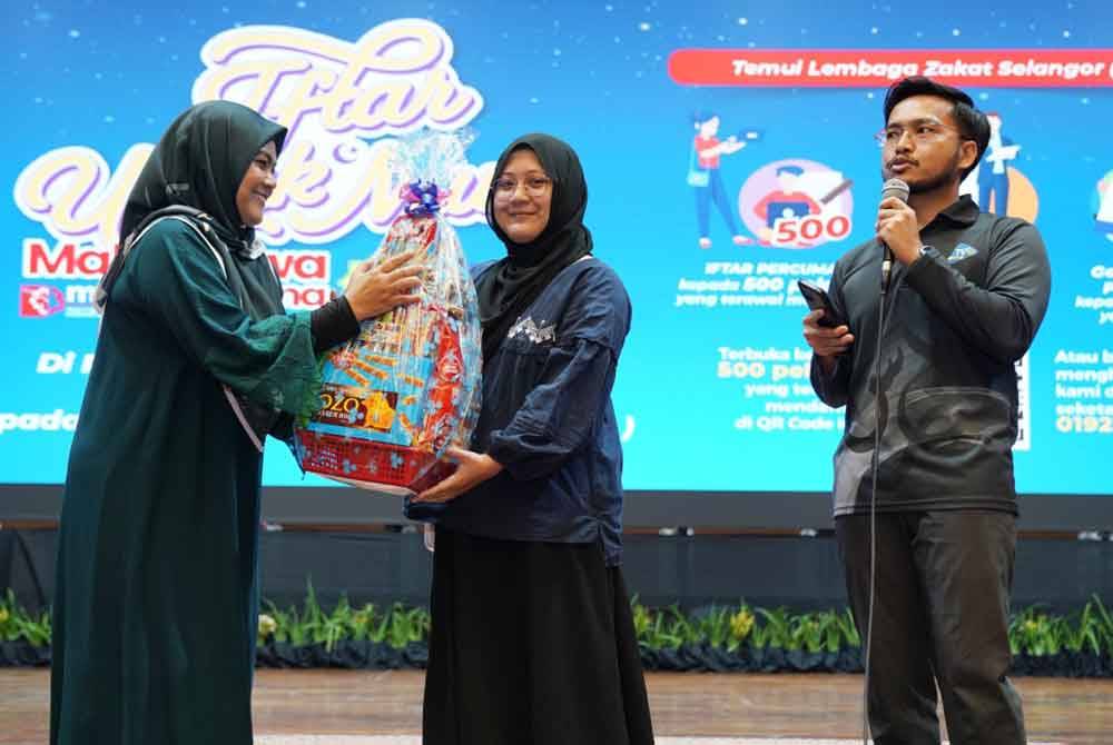 Norazimah (kiri) menyerahkan hamper kepada pemenang kuiz LZS.