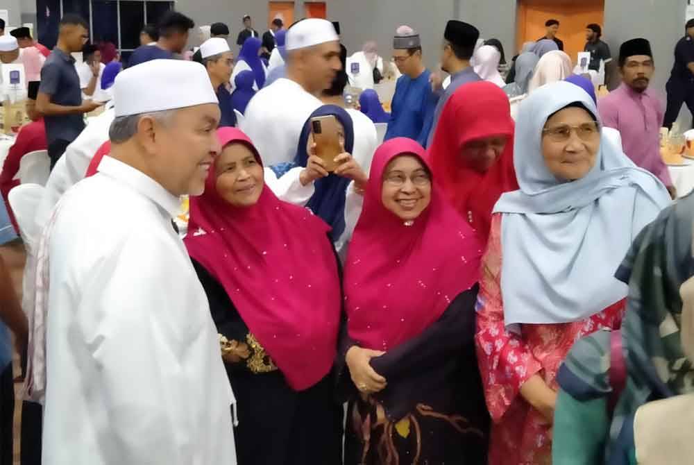 Ahmad Zahid (kiri) menyantuni orang ramai yang hadir ke Majlis Iftar Santunan Kasih Ramadan di MRSM Ulul Albab Felda, Sungkai pada Selasa.