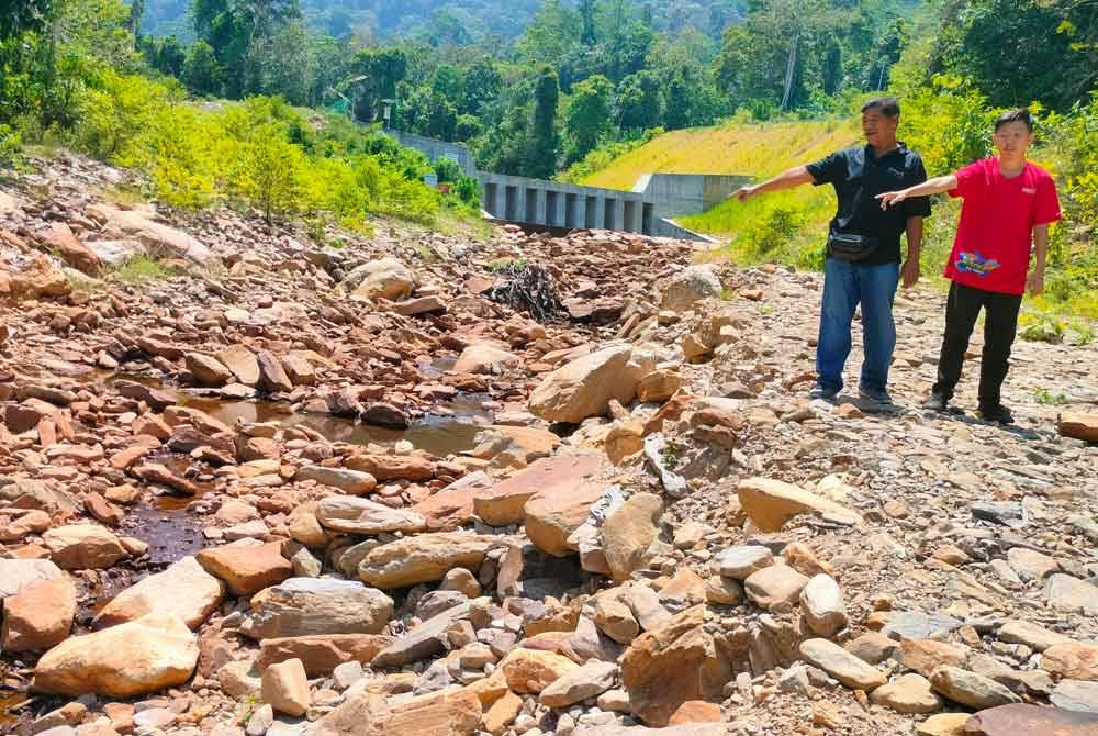 Mohd Said (kiri) menunjukkan keadaan air terjun Titi Hayun yang kering-kontang.