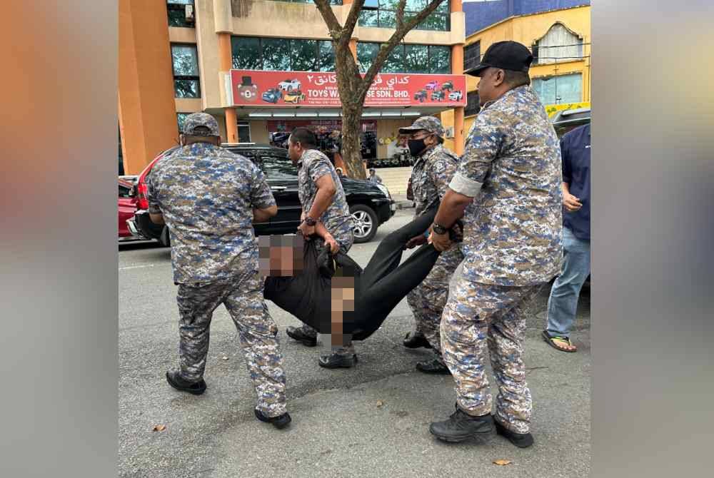 Seorang lelaki yang diusung ke kenderaan pihak berkuasa.