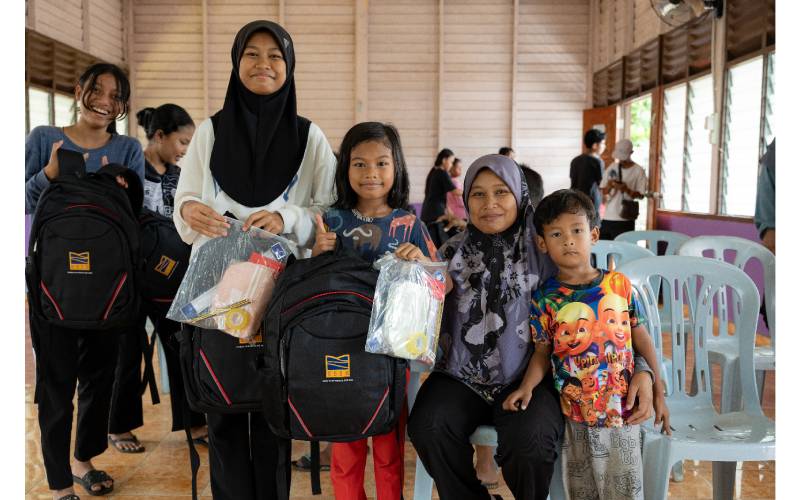 Dua beradik dari Kampung Orang Asli Bukit Serdang bersama ibu mereka menunjukkan kegembiraan selepas menerima sumbangan kelengkapan persekolahan sempena program ‘Back To School KSSB’.