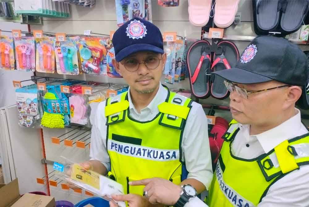 Mohd Fared (kiri) memeriksa stoking ketika operasi pemantauan di sebuah kedai serbaneka di Johor Bahru pada petang Rabu.