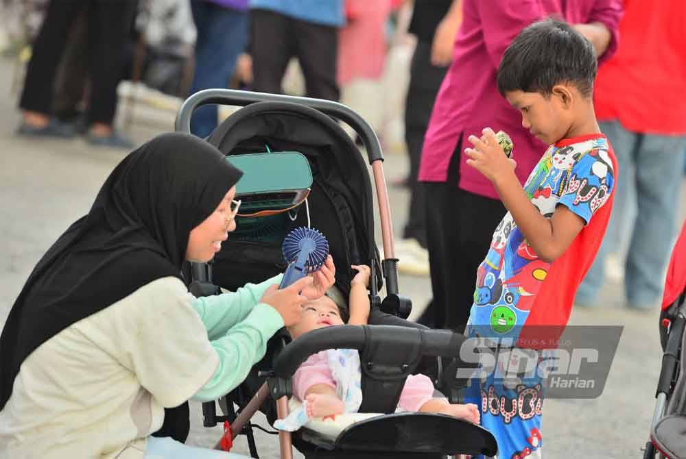 Seorang ibu membawa dua anaknya untuk berbuka puasa di Dataran Karangraf. Foto Sinar Harian-ASRIL ASWANDI SHUKOR