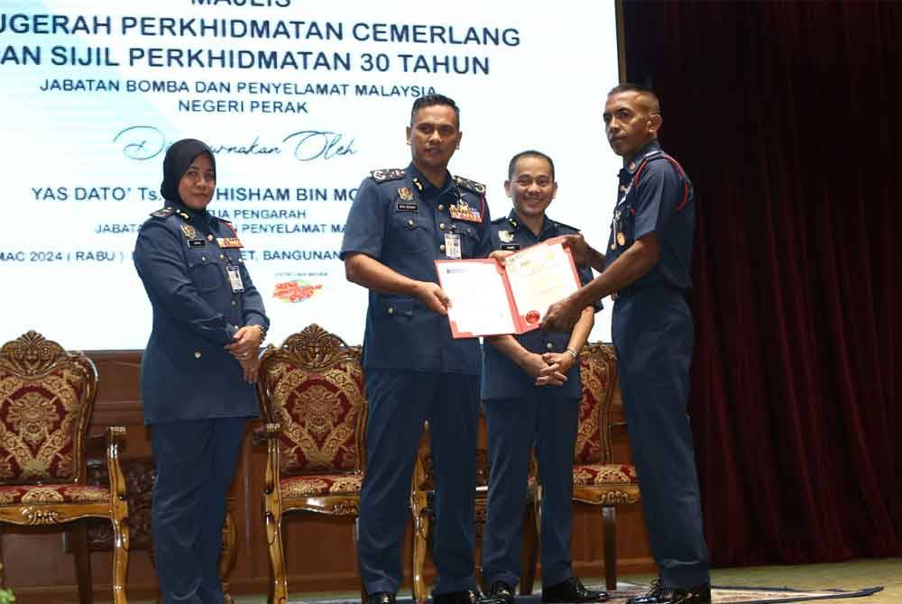 Nor Hisham (tengah) menyampaikan Sijil Perkhidmatan Cemerlang kapada anggota JBPM Perak.