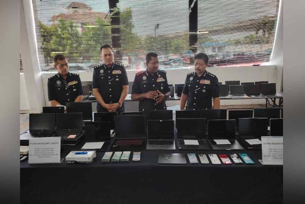 Hussein (dua dari kanan) menunjukkan antara komputer riba yang dirampas dalam serbuan sebuah premis di pusat beli-belah di Subang Jaya pada Isnin.