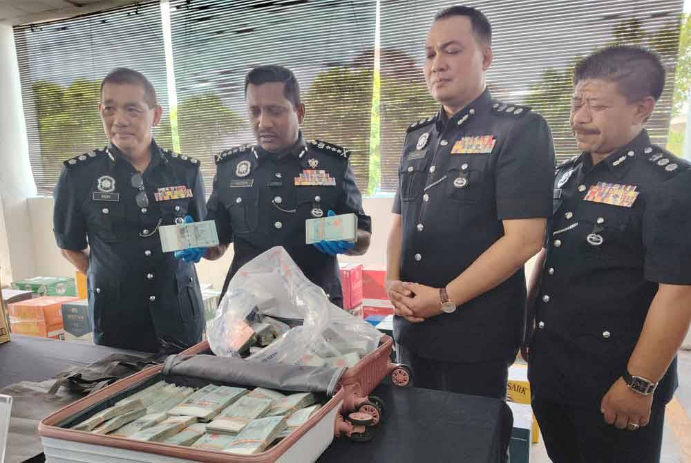 Hussein (dua, kiri) menunjukkan wang tunai dalam bagasi yang ditemui pengawal keselamatan sebuah pusat beli-belah di Petaling Jaya, pada Rabu.