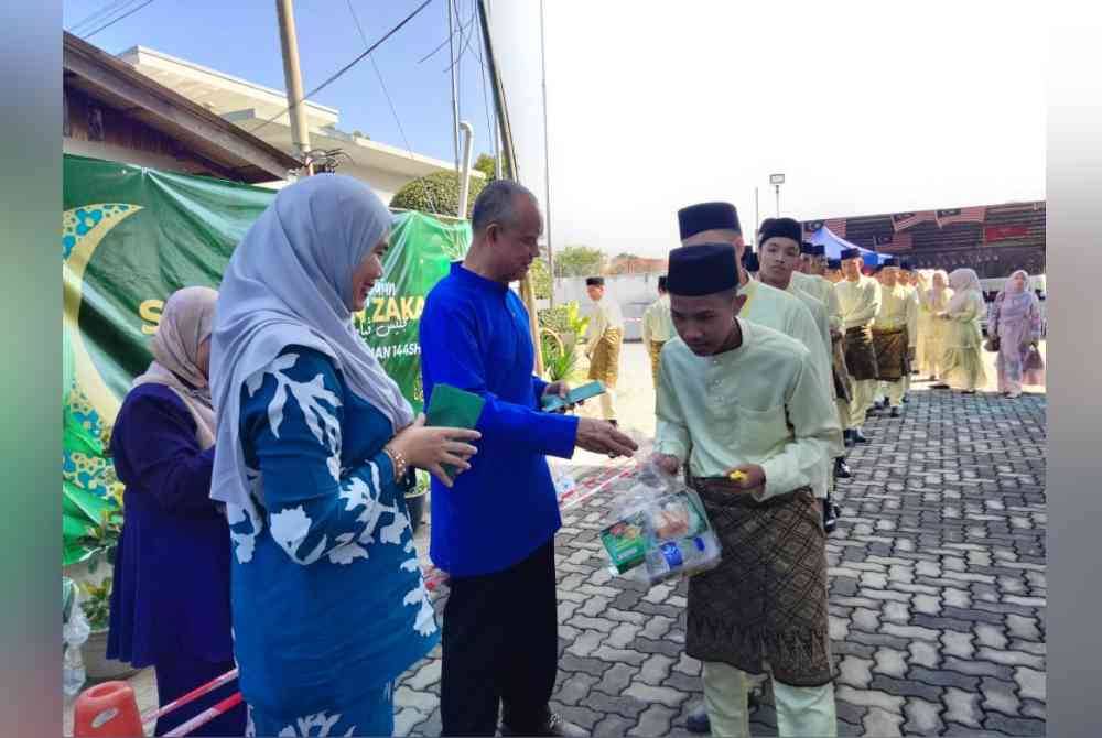 Che Ibrahim (tengah) menyampaikan zakat dan makanan untuk berbuka puasa kepada anak yatim sempena Majlis Penyampaian Zakat Oleh Konsortium E-Mutiara pada Khamis.