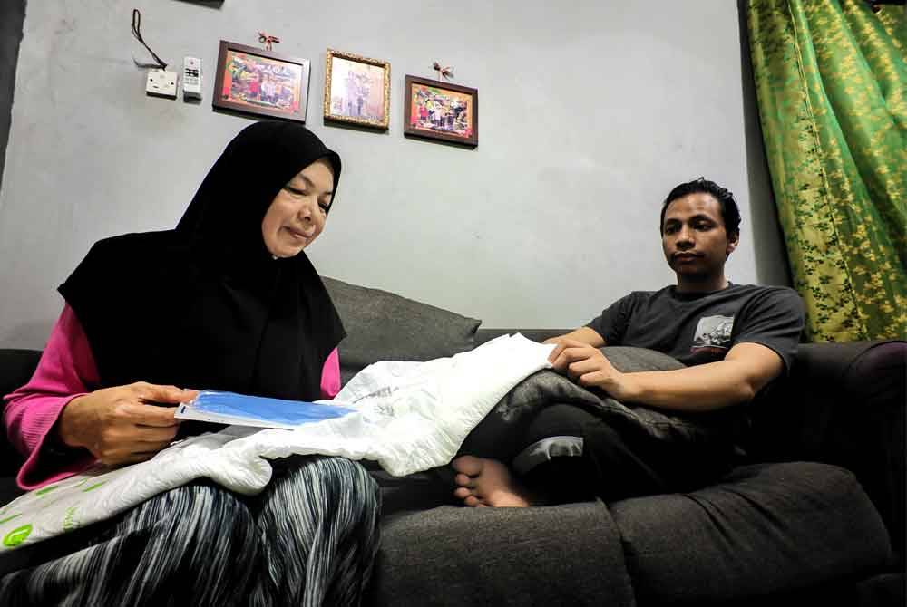 Siti Hajar menunjukkan pelapik yang perlu diletakkan pada lampin buang Muhammad Nasrullah bagi mengelakkan air pada bengkak testisnya mengalir.