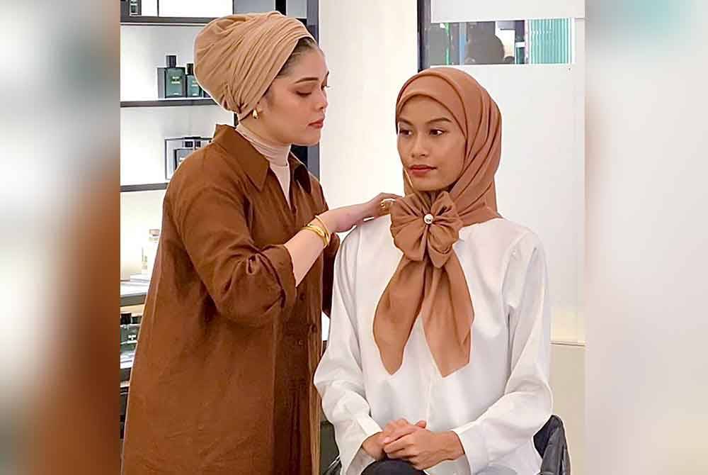 Jurugaya tudung Eka Jamaludin (kiri) menggayakan model dengan stail tudung visor pada bahagian awning yang juga diikat menjadi bentuk riben pada bahagian hadapan. Foto Bernama