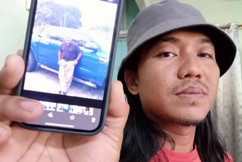 Mohd Syukri menunjukkan foto arwah bapanya yang meninggalkan dunia semasa mengimamkan solat Subuh di Masjid Kampung Sermin, Segamat pada pagi Jumaat.