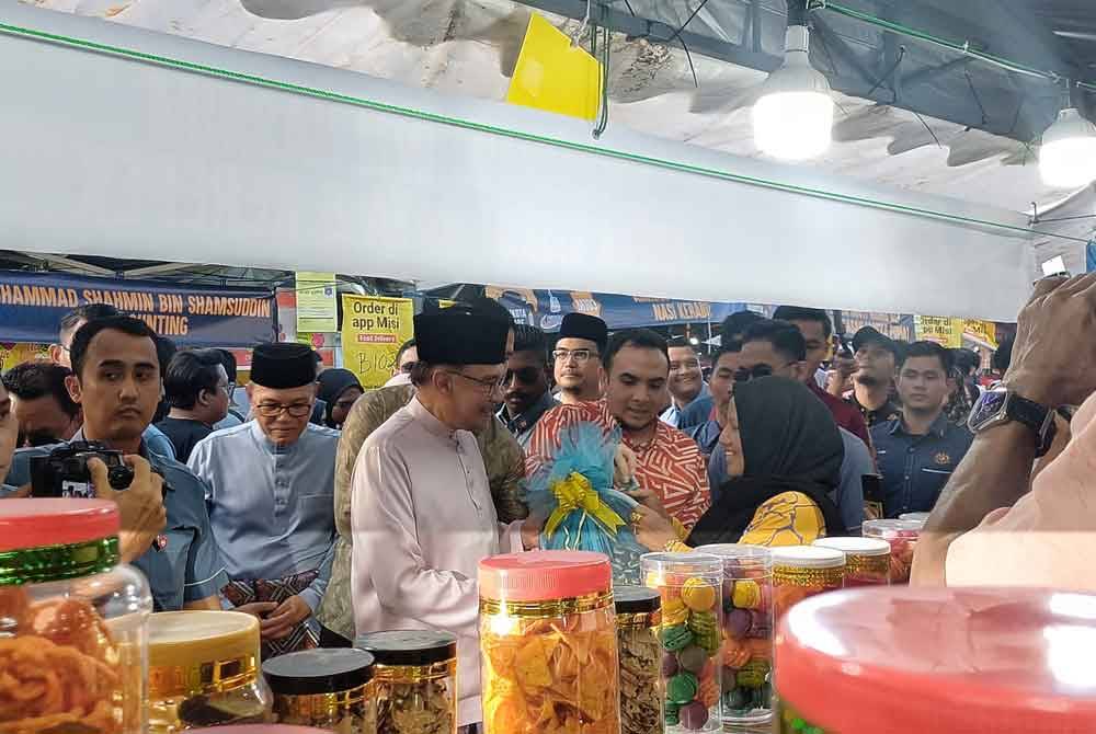 Anwar menerima kuih daripada penjaga di Bazar Ramadan Mahkota Square pada Sabtu.