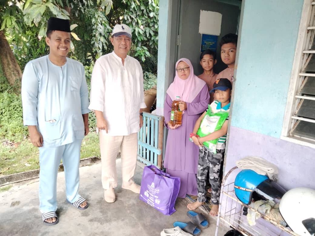 Hasni (dua dari kiri) bersama penerima sumbangan program Temashor Ramadan Majlis Belia Daerah Pontian di Kampung Sanglang, di Pontian.