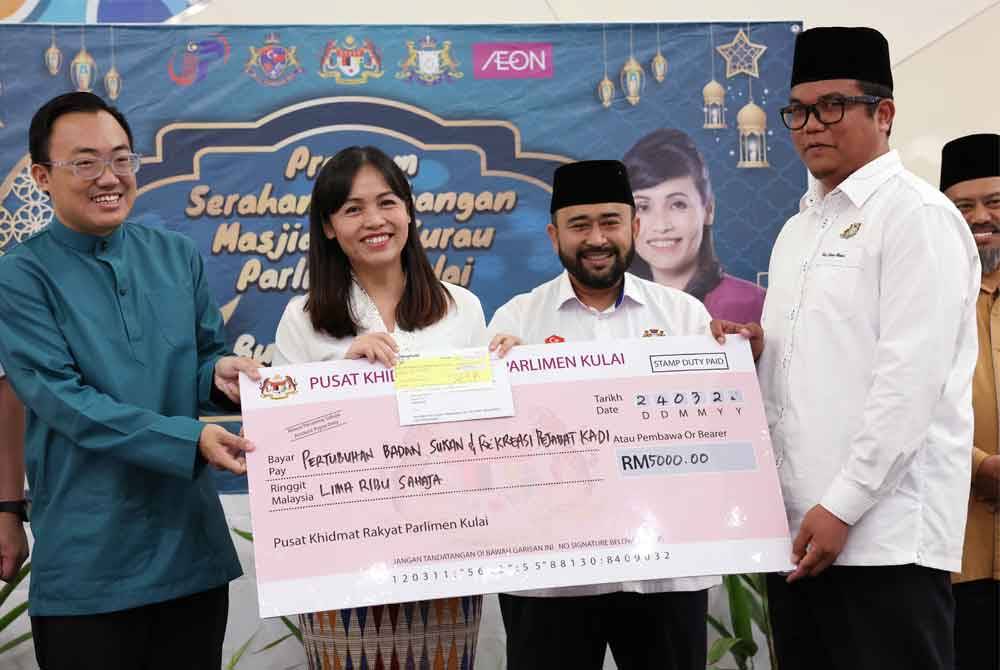 Nie Ching menyerahkan sumbangan replika cek kepada Pengerusi Badan Kebajikan Sukan dan Rekreasi Pejabat Kadi Daerah Kulai, Azamuddin Ahmad (kanan).