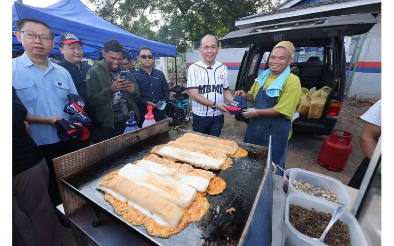 Datuk Bandar Majlis Bandaraya Melaka Bersejarah (MBMB), Datuk Shadan Othman (dua, kanan) bersama Ketua Perniagaan Komersial Petron Malaysia, Mohd Asri Ibrahim (tiga, kanan) menyerahkan topi dan apron kepada salah seorang peniaga di Bazar Ramadan Peringgit, Melaka.
