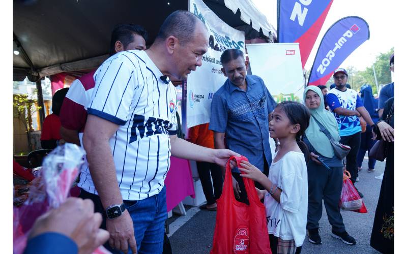 Shadan (kiri) menyerahkan sumbangan iftar kepada salah seorang kanak-kanak yang mengunjungi Bazar Ramadan Peringgit, Melaka. 