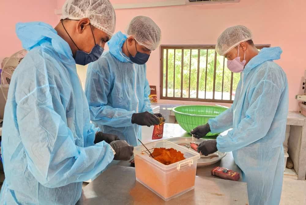 Tiga pekerja Azaruddin mengenakan pelitup diri ketika mengendalikan pembungkusan rempah masak hitam secara manual.