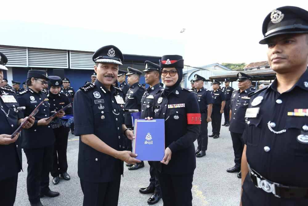 Mohd Yusri (tengah) menyampaikan sijil penghargaan kepada pegawai polis pada perhimpunan sempena Sambutan Hari Polis ke-217 di Ipoh.