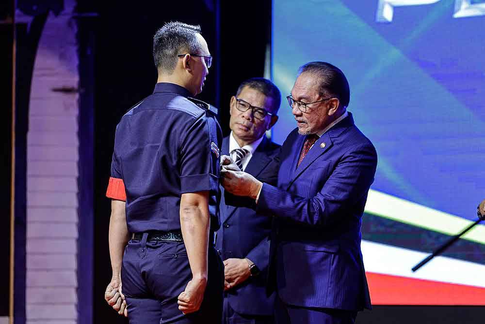 Anwar (kanan) memakaikan pingat Anugerah Juara Integriti kepada penerima sambil diperhatikan Saifuddin pada sambutan Peringatan Hari Polis Ke-217 di Pulapol Kuala Lumpur hari ini. Foto Bernama