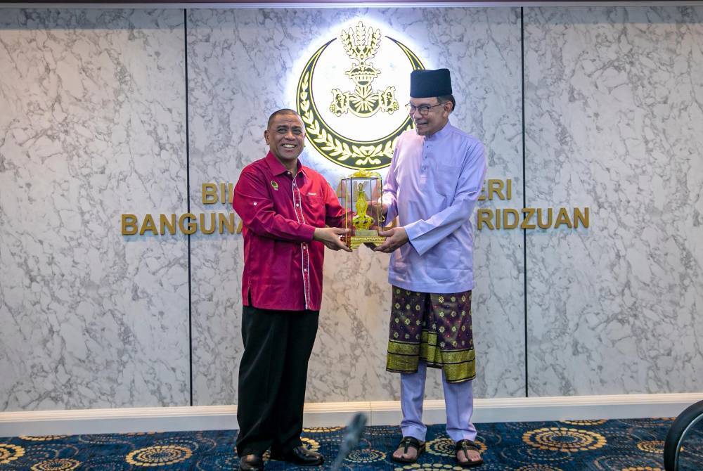 Saarani (kiri) menyampaikan cenderahati kepada Anwar di Bangunan Perak Darul Ridzuan pada Isnin.