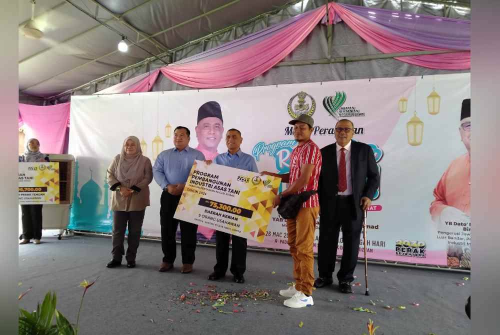 Saarani (tengah) menyampaikan bantuan Program Pembangunan Industri Asas Tani selepas menyempurnakan perasmian Program Riang Ria Raya Promosi dan Jualan Produk Industri Asas Tani di padang Bangunan Seri Perak Darul Ridzuan di sini pada Selasa.