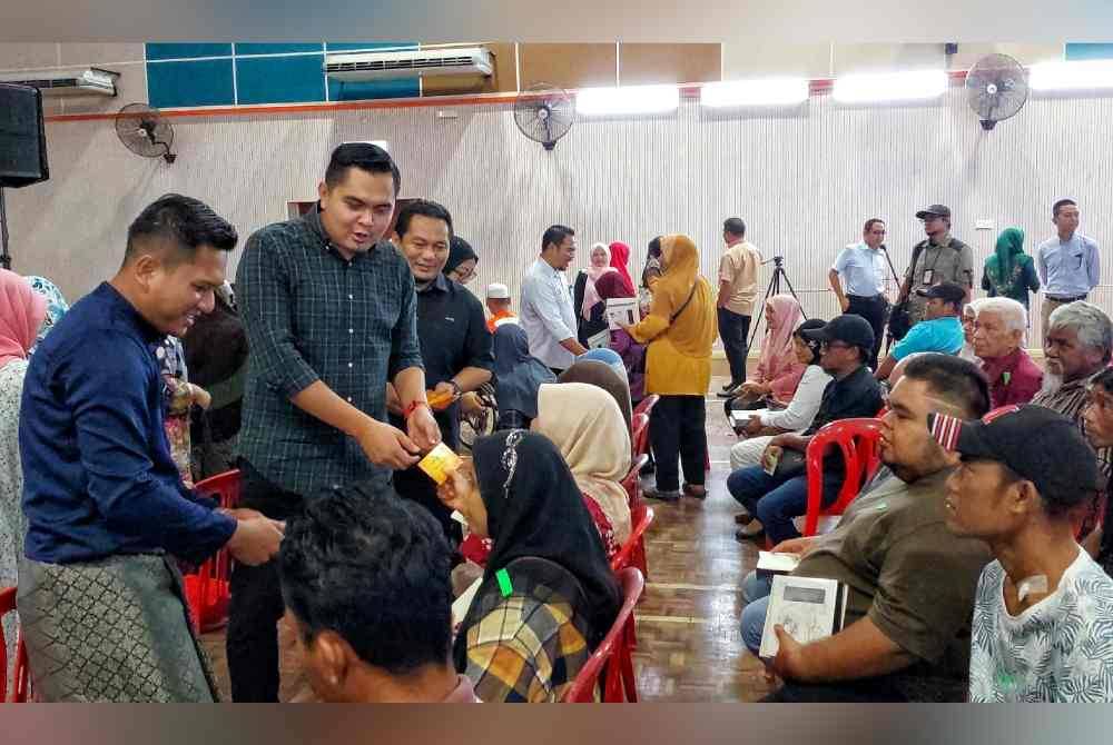Muhamad Akmal (dua dari kiri) ketika menyampaikan sumbangan kepada penerima pada Program Penyampaian Sumbangan Hari Raya Aidilfitri Parlimen Jasin kepada asnaf di Lipat Kajang, pada Selasa.