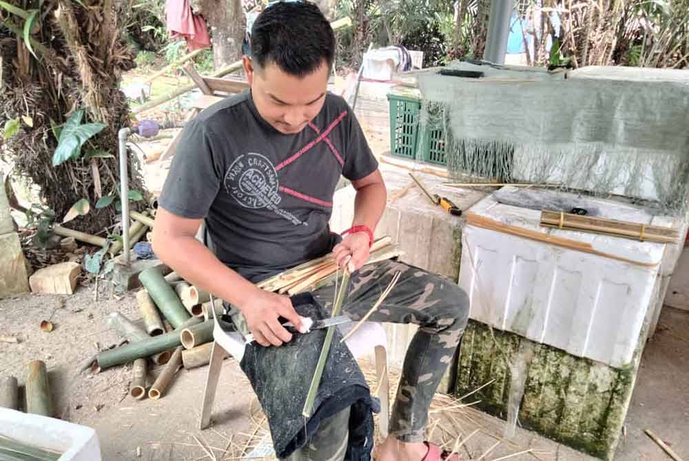 Hasbullah meraut buluh iaitu salah satu proses membuat perangan