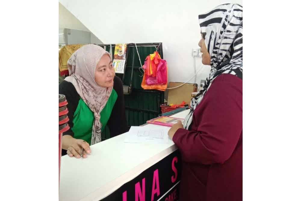 Norazlina (kiri)ketika melayani seorang pelanggannya.