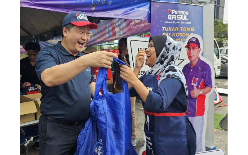 Danny Chen menyampaikan beg cenderahati kepada peniaga di reruai Petrol Gasul bazar Ramadan Stadium Perak di Ipoh.