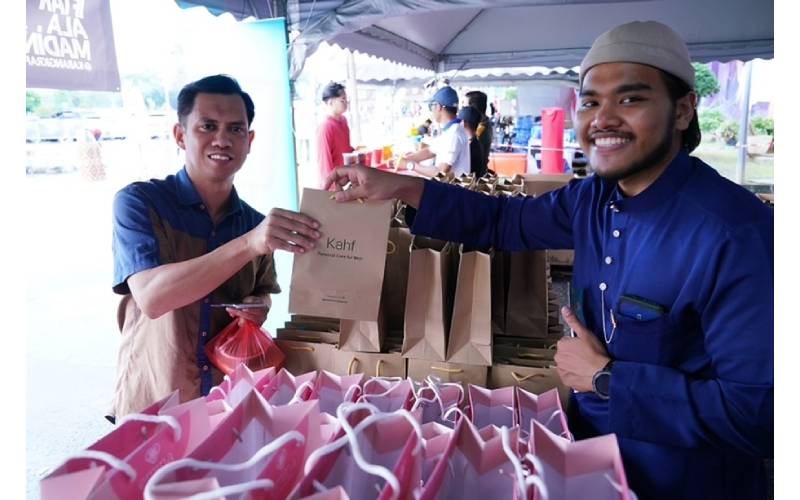 Salah seorang pengunjung menerima cenderahati daripada Kahf ketika hadir pada majlis Iftar Ala Madinah@Karangkraf, semalam.