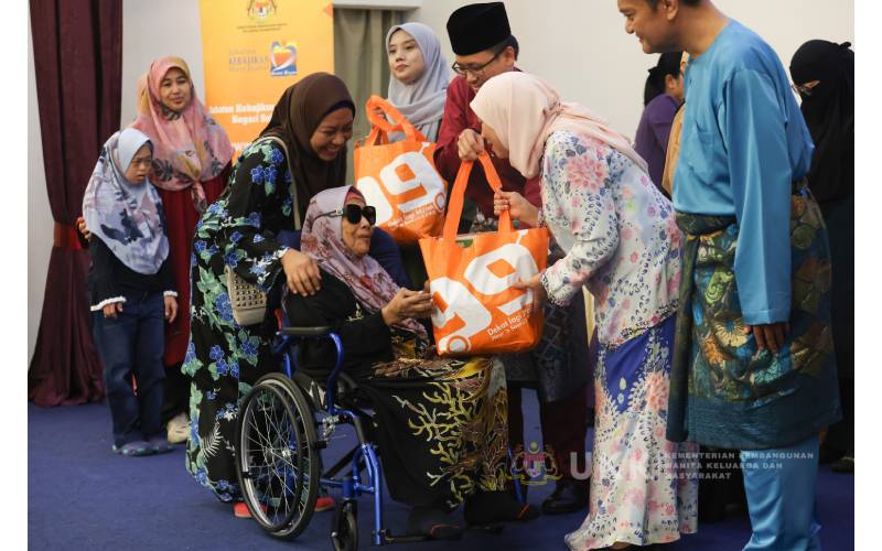 Nancy menyerahkan sumbangan kepada penerima berupa barangan keperluan asas sebagai persediaan sambutan Aidilfitri kepada salah seorang penerima. 