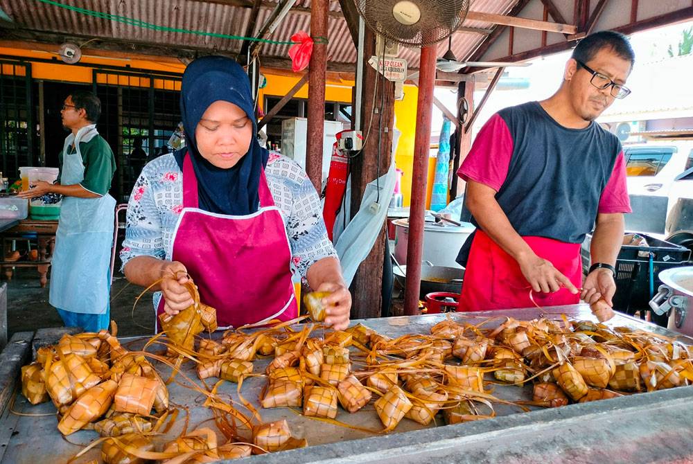 Mohamad Zaim membantu pekerjanya mengikat empat biji ketupat sebelum dijual kepada pelanggan.
