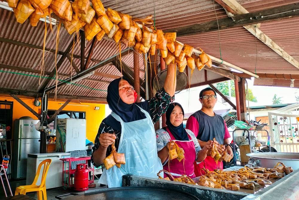 Pekerja Mohamad Zaim sedang mengantungkan ketupat yang telah direbus dan siap untuk dijual.