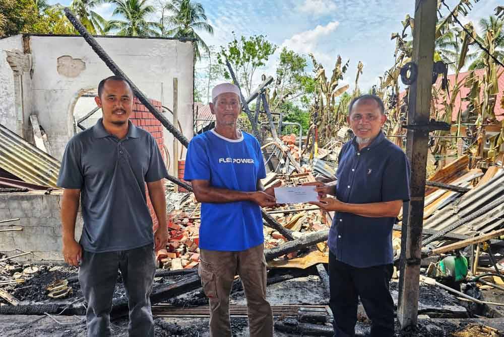 Razak (kanan) menyerahkan sumbangan kepada Mohd Isa (tengah) pada Rabu.