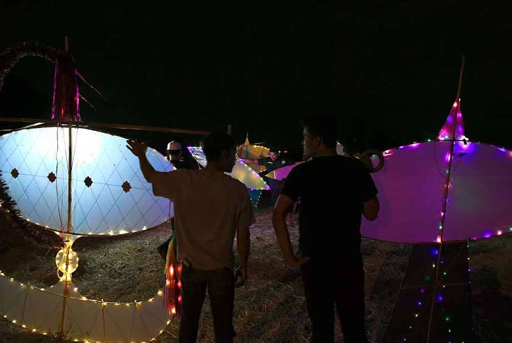 Dua anak muda bersedia untuk menerbangkan wau masing-masing di Kampung Panchor, Pendang pada malam Rabu.