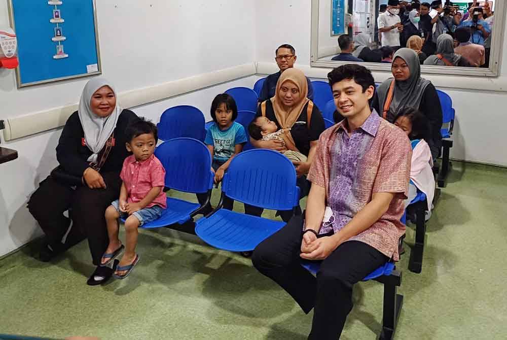 Tengku Hassanal (kanan) bergambar dengan pengujung yang duduk di kerusi menunggu Jabatan Kecemasan HTAA pada Khamis